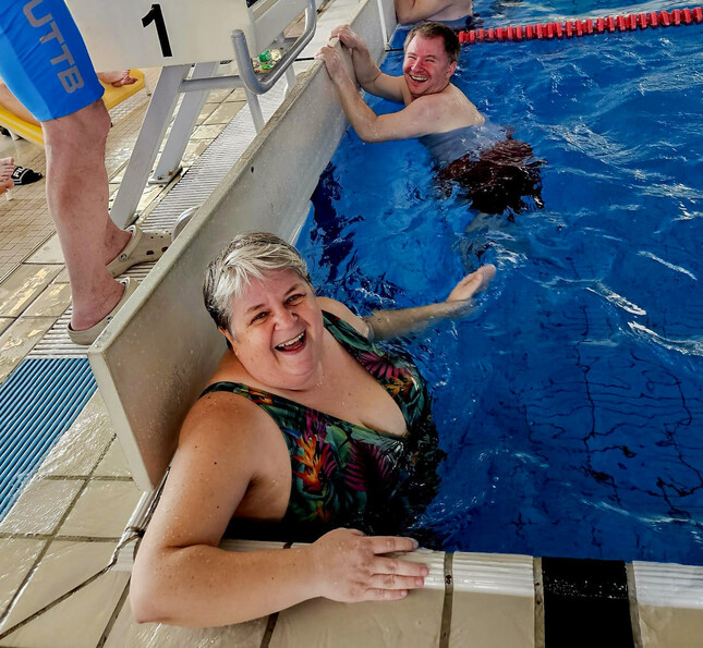 Bewohner*innen lächeln am Beckenrand in die Kamera.