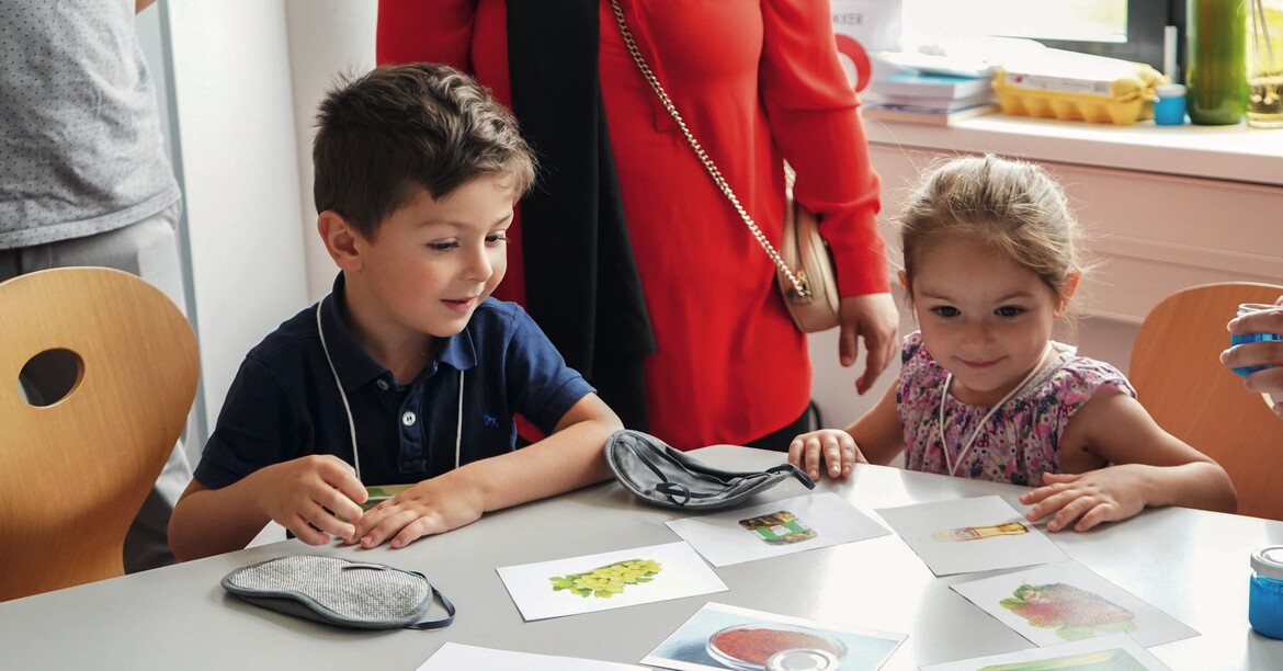 Zwei Kinder spielen fröhlich an einem Tisch. 