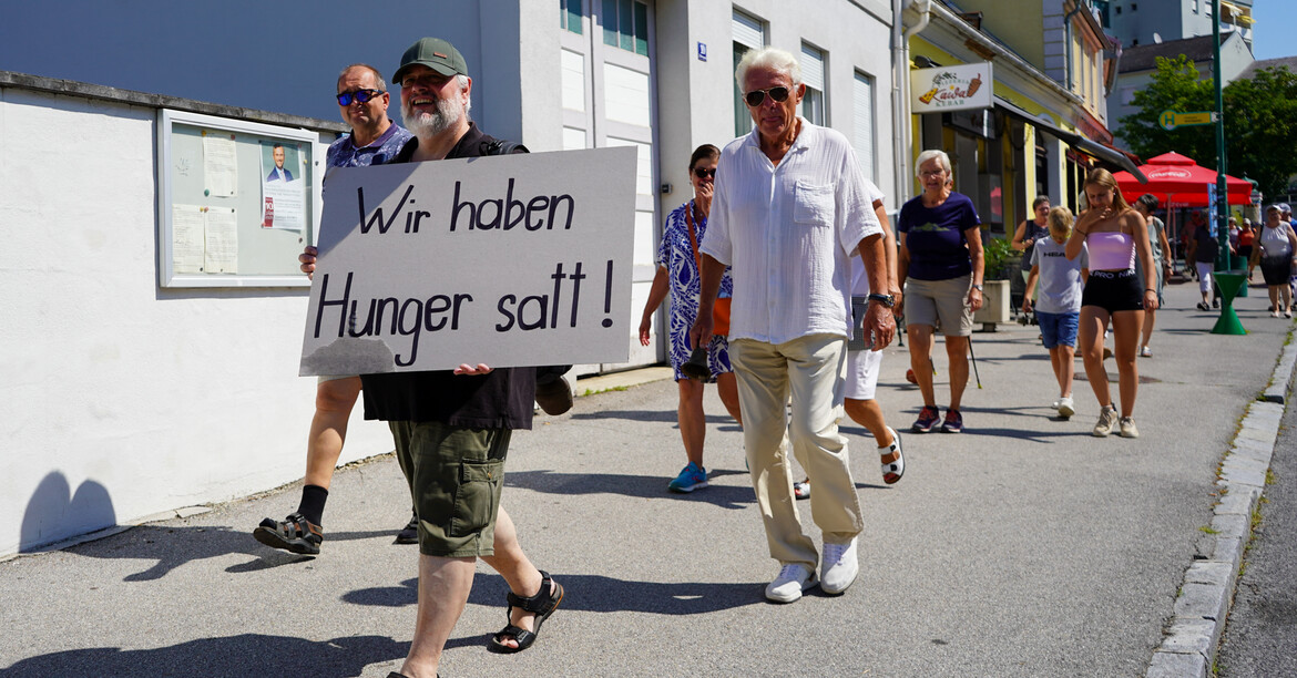 Freiwillige und Mitglieder der PfarrCaritas wandern durch durch Pinkafeld und halten ein Schild auf dem "Wir haben Hunger satt!" steht.