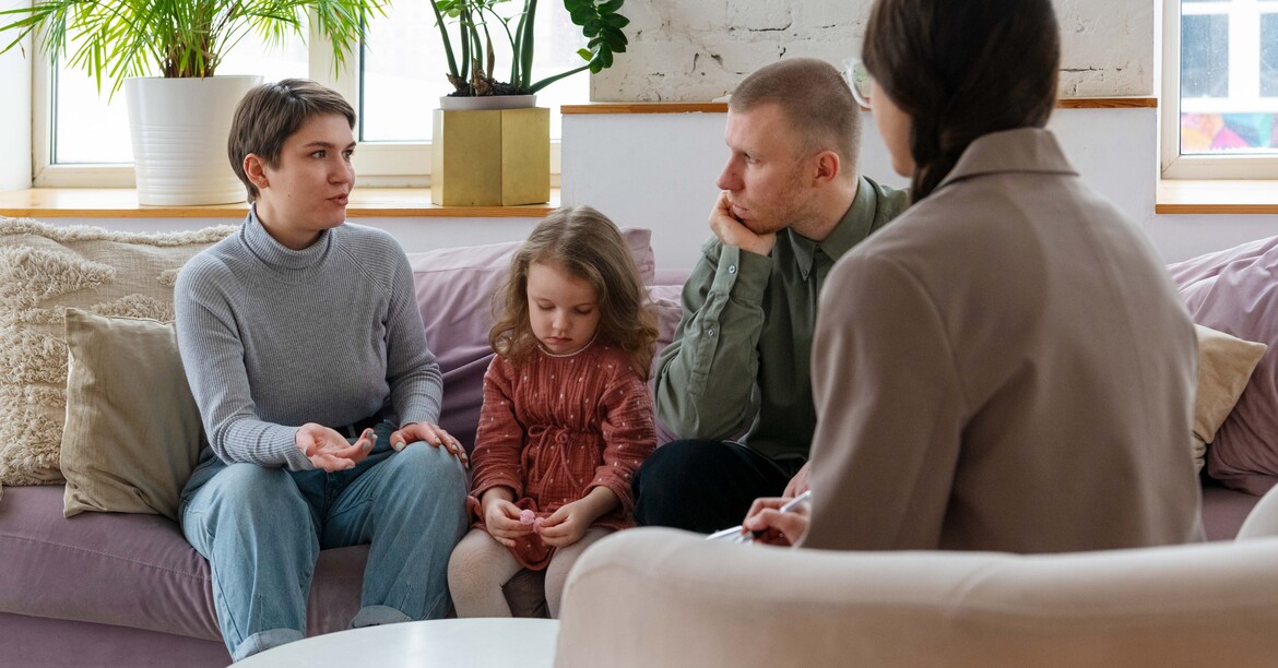Eltern sitzen mit ihrer Tochter bei einem Beratungsgespräch.