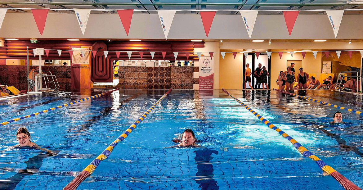 Mehrere Menschen schwimmen auf Bahnen in einem Schwimmbad.