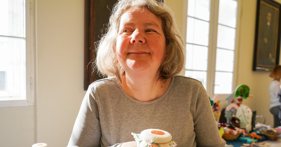 Eine Frau lächelt mit einem Produkt vom Ostermarkt in der Hand in die Kamera.