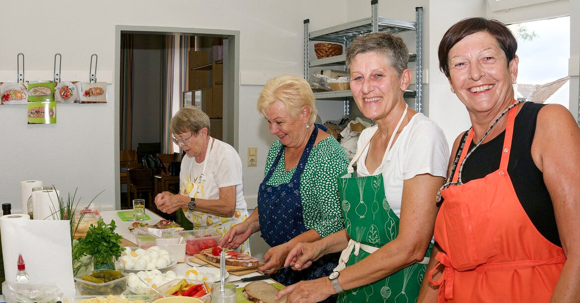 Vier ältere Damen haben sichtlich Freude bei der Essenszubereitung. 