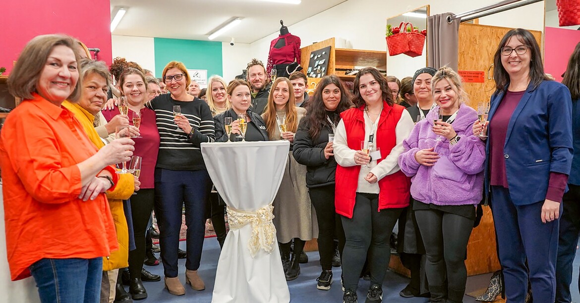 Mehrere Menschen stoßen mit einem Sektglas auf das Jubiläum an. 