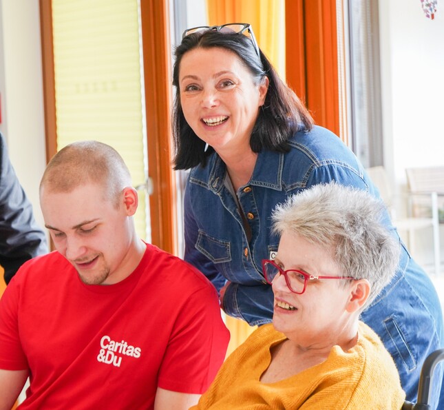 Mehrere Caritas Mitarbeiter*innen zusammen mit einer Bewohnerin.